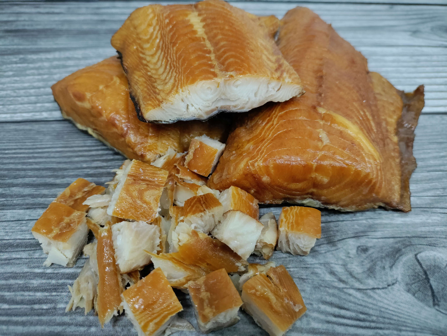 Smoked wild Alaskan black cod (sablefish) fillets and cubed pieces on a wooden board.