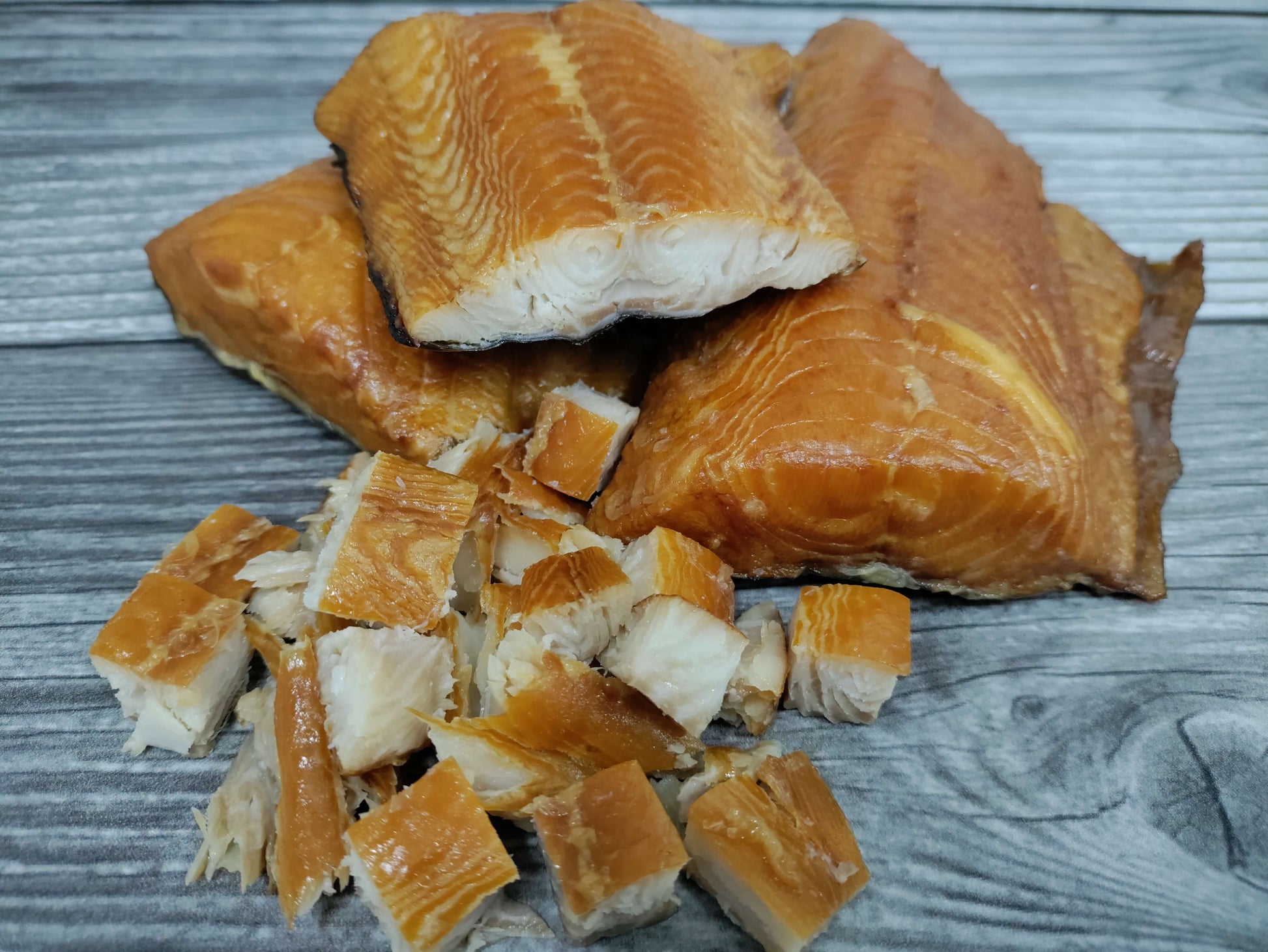 Smoked wild Alaskan black cod (sablefish) fillets and cubed pieces on a wooden board.