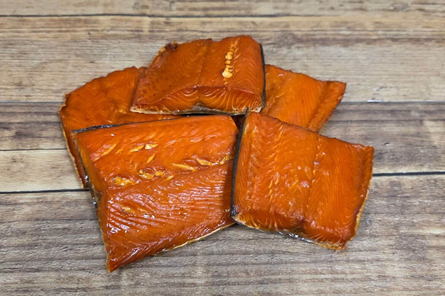 Wild Alaskan smoked salmon snack pieces on a rustic wooden surface