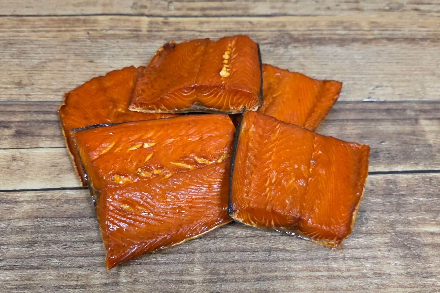 Wild Alaskan smoked salmon snack pieces on a rustic wooden surface