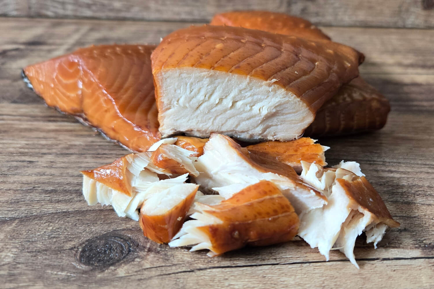 Close-up of smoked ivory king salmon chunks on a wooden surface.