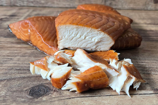 Close-up of smoked ivory king salmon chunks on a wooden surface.
