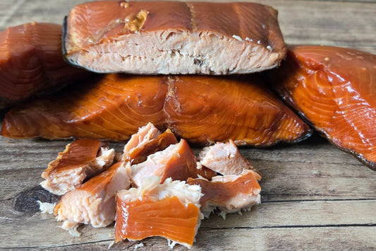 Smoked wild Alaskan king salmon fillets and pieces on a wooden board.