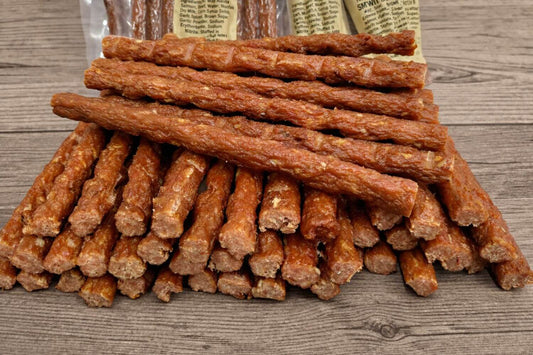 Wild Alaskan smoked salmon snack sticks stacked on rustic wood surface.