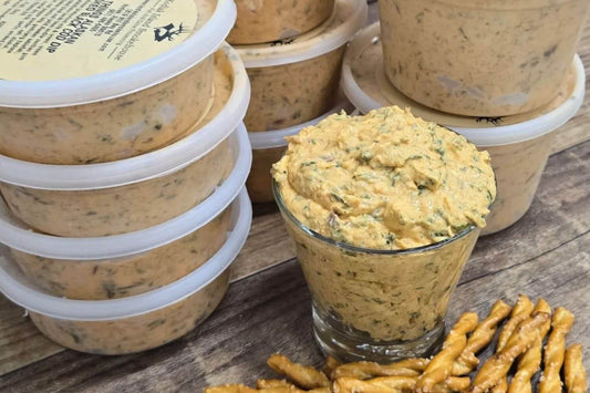 Containers of spicy smoked black cod dip with a bright, creamy texture on a rustic wooden surface.