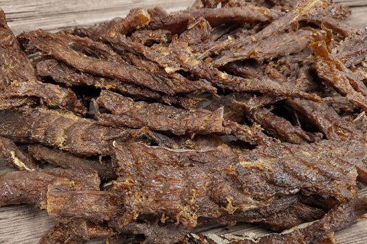 Sweet teriyaki-seasoned wild cod jerky strips on a wooden board.